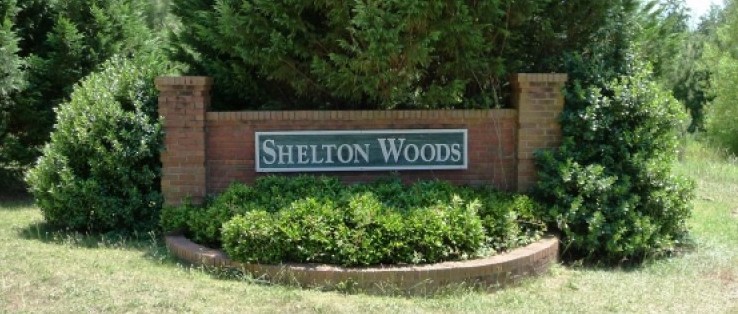 Shelton Woods community entrance, close to top chiropractor in Opelika, AL, surrounded by lush greenery and shrubs.