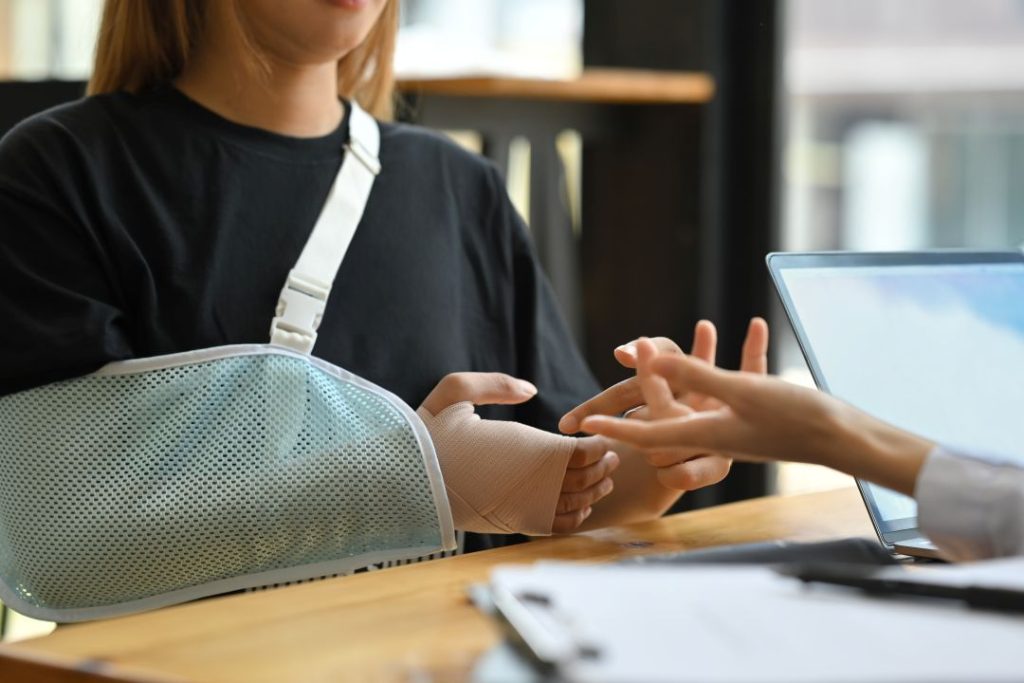 Patient with arm in sling consults chiropractor in Auburn, AL for recovery support.