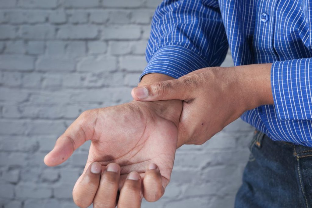 Person holding their wrist in pain, seeking help from a chiropractor in Auburn, AL for relief and treatment.