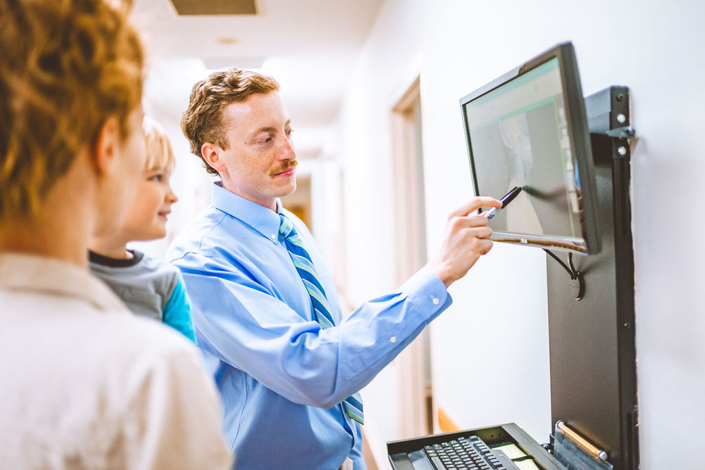 Chiropractor in Auburn, AL explains patient X-ray results on screen for family consultation.